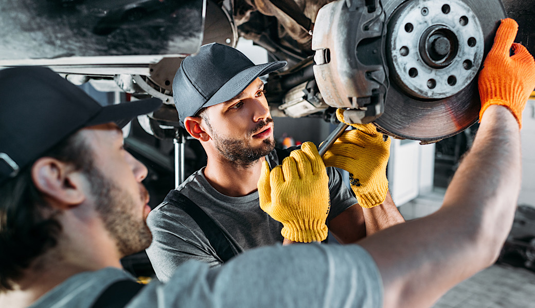 professional male mechanic repairing car without wheel in auto repair shop